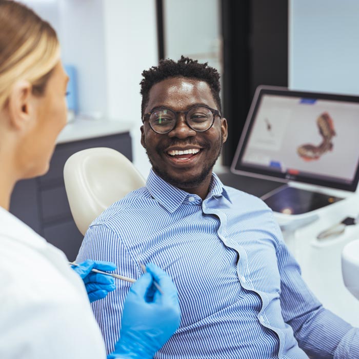man smiling while dentist explains procedure
